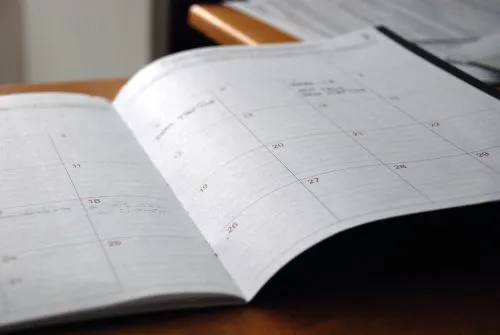 Open planner on a table showing a monthly calendar with handwritten notes.