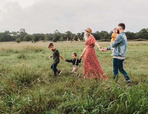 Family walking hand in hand through a grassy field.