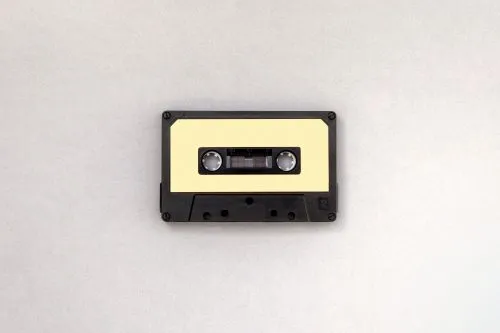 A vintage cassette tape with a beige label on a light gray background.
