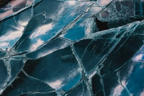 Shattered glass reflecting a cloudy sky.
