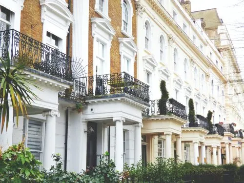 Row of elegant townhouses with iron balconies and columns.