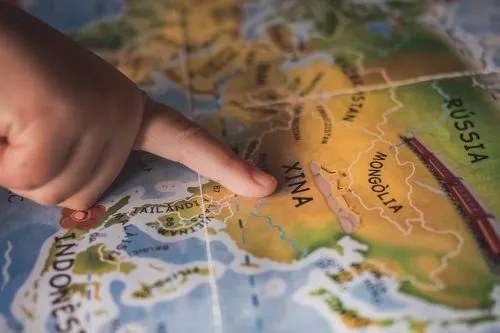 Child's finger pointing at China on a colorful map.