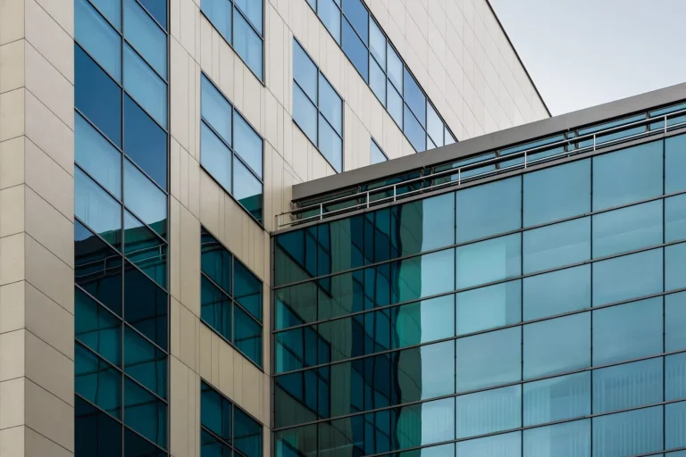 Modern glass and concrete building with reflective blue windows.